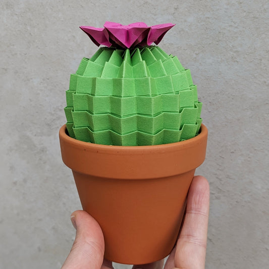 large lime green folded paper cactus with pink origami flower on top in a terracotta pot