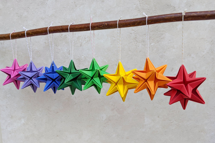 colourful origami paper star baubles hanging from a branch