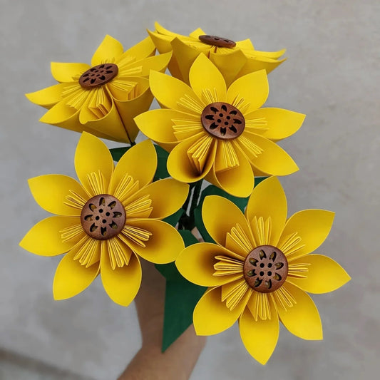 Bouquet of five yellow handmade origami sunflowers with brown button centres, held together in a bunch by a hand