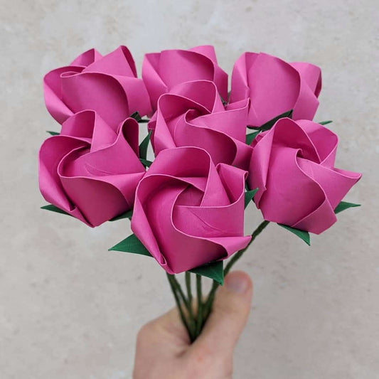 seven hot pink paper rose flowers gathered into a bouquet by hand