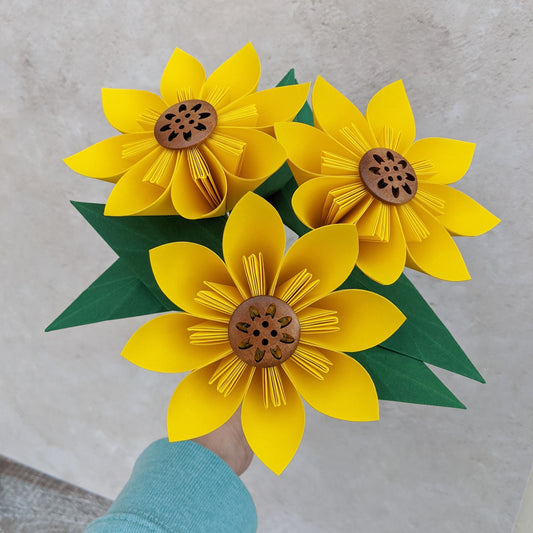Bouquet of 3 bright yellow origami sunflowers with 2 green leaves on each stem, all folded from recycled paper
