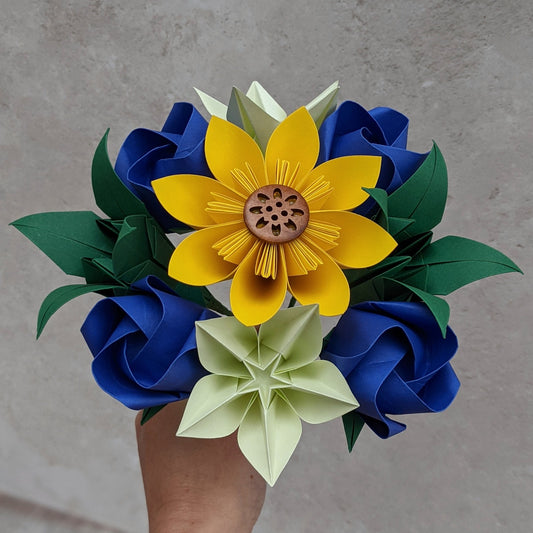 Origami paper bouquet with a variety of flowers in yellow, greens and blue with a sunflower in the centre