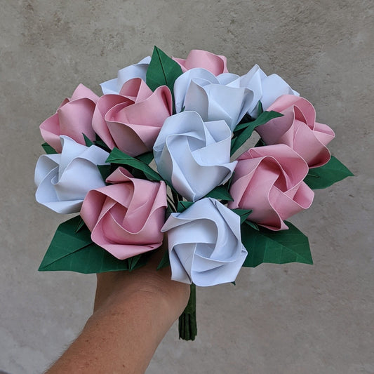 A big bouquet of one dozen pink and white origami rose flowers interspersed with dark green origami leaves
