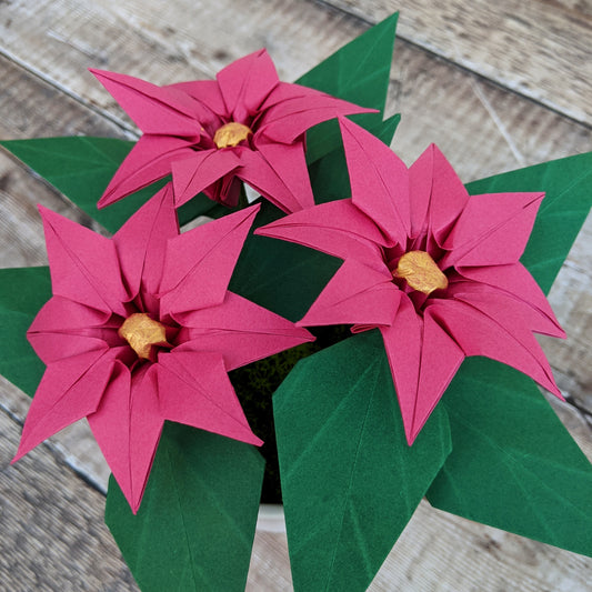 Pink origami paper poinsettia faux plant with green leaves in pot